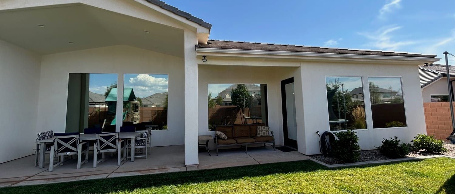 Back of a St. George home, its ground-floor windows facing the patio and irrigated lawn