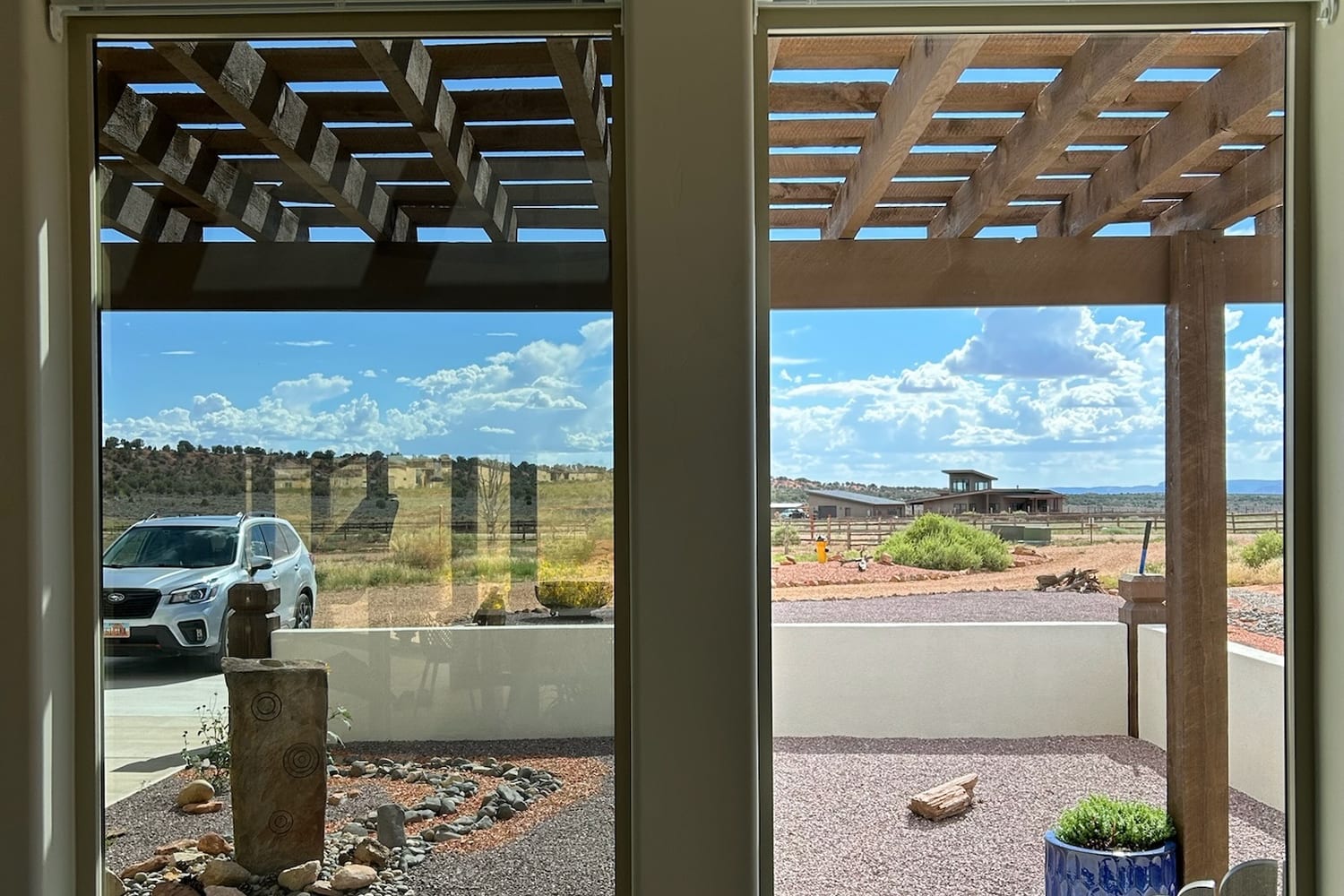 Interior windows and sliding track looking out to a pergola and gravel courtyard