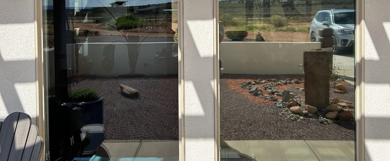 Two ground-floor windows seen from the patio, with an outdoor chair set close to the glass