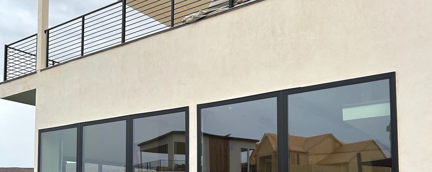 Fresh stucco finished right up to the frames of a modern home's ground-floor glass