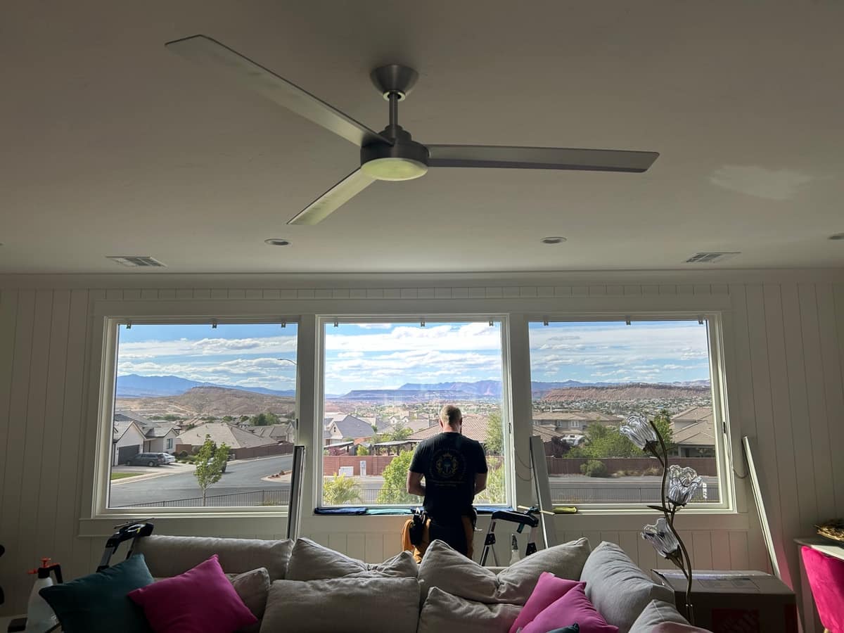 Imperial installer fitting window film with a Southern Utah valley view