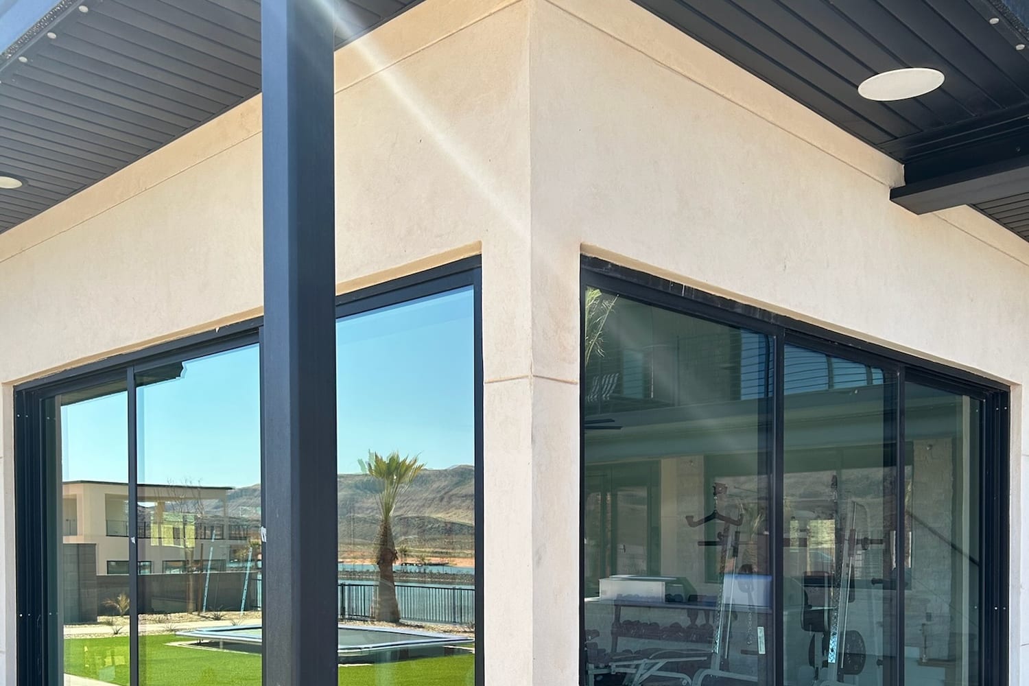 Corner sliding doors with reflective film mirroring the pool and desert outside