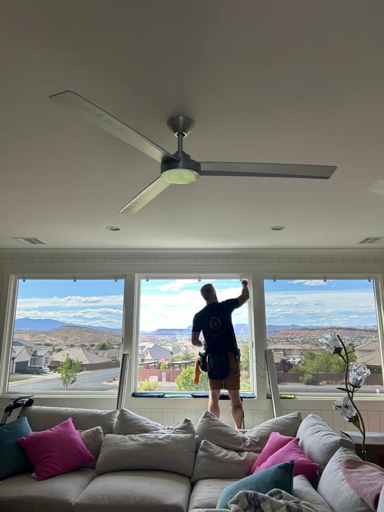 Imperial installer applying window film at a picture window with a valley view