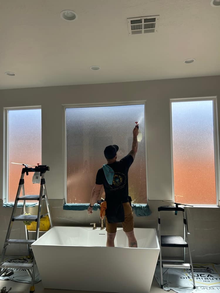 Installer applying frosted privacy film to tall windows